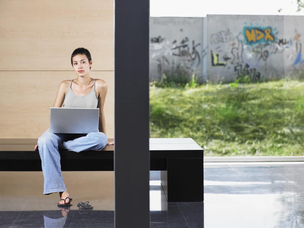 Woman working on laptop with graffiti in background